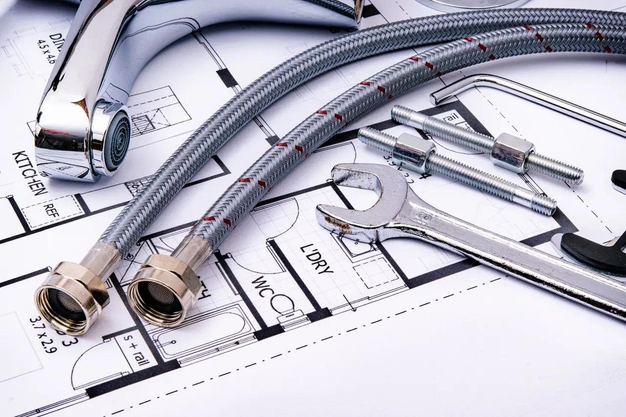 Flexibele aansluitslangen, een kraan en een steeksleutel op een installatietekening