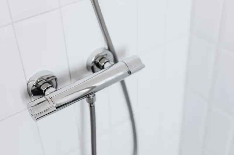 Thermostatische douchekraan op een witte tegelwand